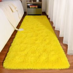 a bright yellow rug is on the floor next to a bed