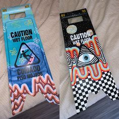 two skateboards are laying on a bed with the covers pulled down and one has an upside down sign that says caution wet floor