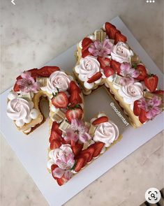 two slices of cake with strawberries and flowers on them are arranged in the shape of a letter