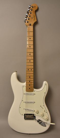 an electric guitar sitting on top of a gray wall next to a string attached to the neck