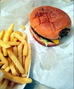 a hamburger and french fries sitting on top of a white paper wrapper next to each other