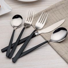 four spoons and two forks on a table with plates, napkins and utensils