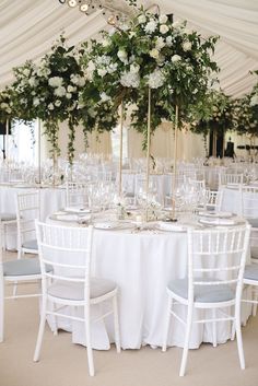 the table is set up with white flowers and greenery for an elegant wedding reception