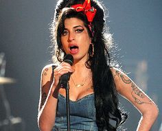 a woman with long black hair holding a microphone and wearing a red bow on her head