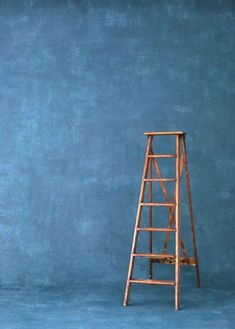 a wooden ladder leaning against a blue wall