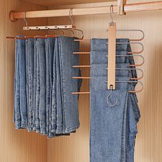 several pairs of blue jeans hanging on clothes pins in a closet with wooden hangers