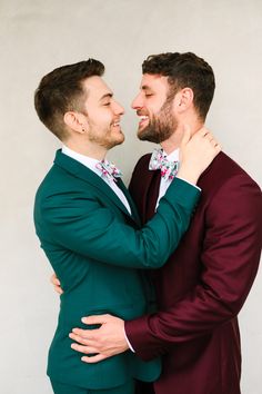 two men in suits are hugging each other and looking into one another's eyes