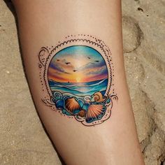 a tattoo on the leg of a woman with seashells and sunset in the background