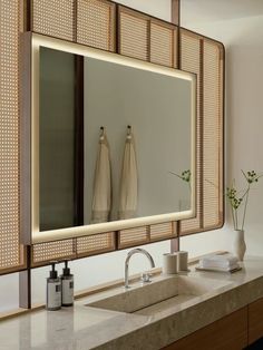 a bathroom sink with a large mirror and two vases on the counter top in front of it