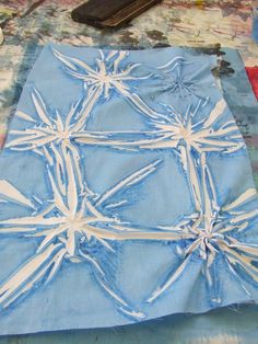 a blue and white piece of cloth with snowflakes on it, next to a cell phone