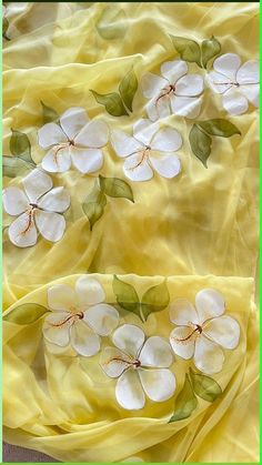 white flowers are on yellow fabric with green leaves and stems in the center, as if they were hand painted