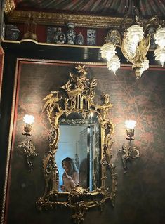 a woman taking a selfie in front of a mirror with chandeliers on the wall