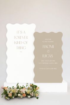 the wedding stationery is displayed on top of a white pedestal with flowers and greenery