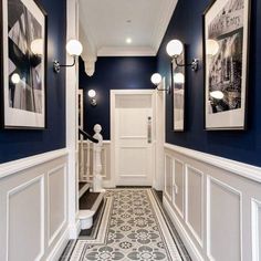 a hallway with blue walls, white trim and pictures hanging on the wall above it