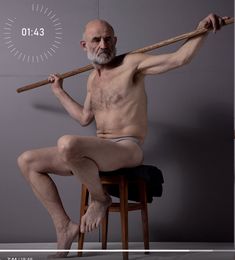 an old man sitting on a stool holding a stick