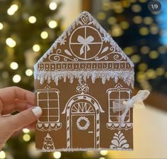 someone holding up a gingerbread house with icing on it