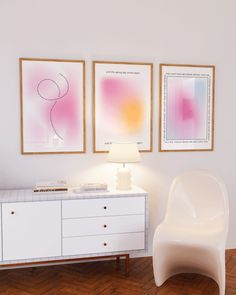 a white chair sitting next to a dresser in a room with paintings on the wall