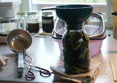 a jar filled with green beans sitting on top of a counter next to scissors and other items