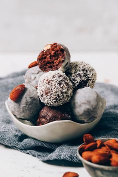 a white bowl filled with chocolate covered donuts and almonds on top of a blue towel