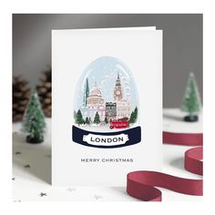 a christmas card with the london skyline in a snow globe on top of it, surrounded by trees