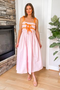 Perfect for Spring and Summer, our Chasing Sunsets Contrast Bow Midi Dress in Pink features a smocked bust with contrast bow detail in orange, tie up bow straps, elastic waist, and flowy skirt. 100% Rayon. Model Measurements: Height 5'5", Bust 33, Waist 25, Hips 33. Wearing a size Small. Bow Straps, Chasing Sunsets, Orange Tie, Style Steal, Outerwear Vest, Jumpsuit Shorts Rompers, Pink Midi Dress, Flowy Skirt, Short Rompers