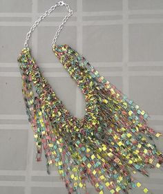 a multicolored necklace is displayed on a gray surface with a chain attached to it