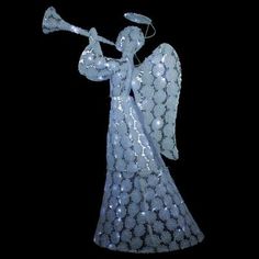 an angel with a trumpet in its hand on a black background is lit up at night