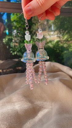 a pair of pink and green beaded earrings hanging from a hook on a window sill