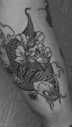 a black and white photo of a fish with flowers on it's leg tattoo