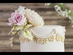 a wedding cake decorated with flowers and pearls