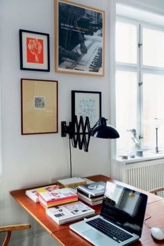 a laptop computer sitting on top of a wooden desk next to a lamp and pictures