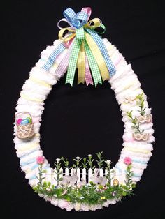 a wreath made out of yarn with flowers and eggs in it on a black background