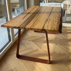 a wooden table sitting on top of a hard wood floor next to a glass door