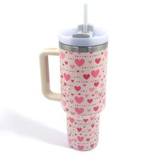 a pink and white cup with hearts printed on the side, in front of a white background