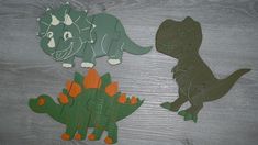 paper cutouts of dinosaurs on a wooden surface with one dinosaur and the other an orange