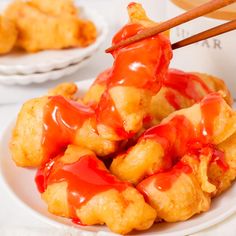 chopsticks sticking out of fried food on a plate with sauce and ketchup