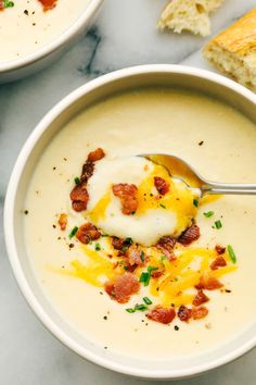 two bowls of soup with bacon, cheese and sour cream in them on a marble surface