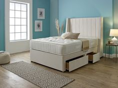 a white bed sitting in a bedroom next to a window and rug on top of a hard wood floor