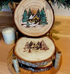 two wooden coasters sitting on top of a table next to a candle and christmas tree