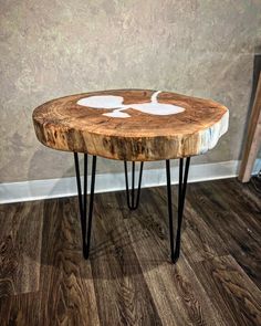 a wooden table with black hairpin legs and a white design on the top, sitting in front of a wall