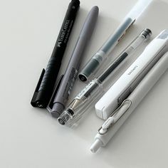 three different pens sitting next to each other on top of a white surface with one pen in the middle