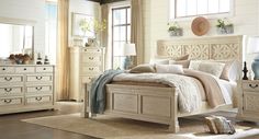 a white bed sitting in a bedroom on top of a wooden floor next to a window