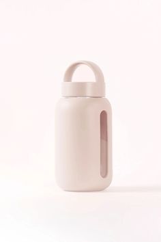 a white ceramic container with a handle on the front and side, against a plain background