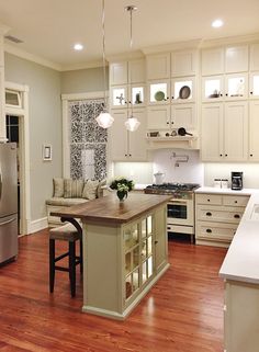 a large kitchen with white cabinets and wood flooring, an island in the middle