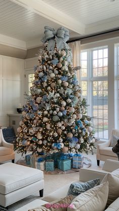 a decorated christmas tree in a living room with blue and silver ornaments on the top