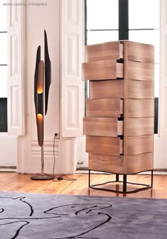 a tall wooden cabinet sitting next to a lamp on top of a hard wood floor