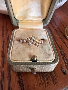 an open ring box with three pearls in it sitting on a table next to a pair of shoes