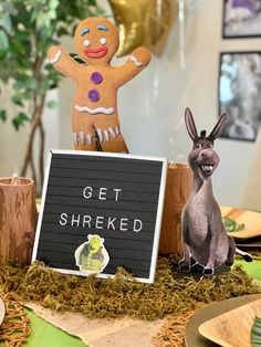 a table topped with two figurines and a sign that says get shreked