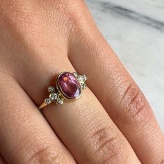 A vibrant Pink tourmaline is set in Emily's 14k gold Trefoil cluster setting with a freeform band. We originally saw this as being a unique engagement ring but it would be just as wonderful as an everyday bit of sparkle and looks phenomenal with our halo bands Approximate stone size: 9mm x 7mm TCW tourmaline: 1.2ct TCW diamonds: .12ct Mohs Stone Hardness: 7.5-8 This one of a kind piece is handmade with love in Emily's Hudson Valley studio. If you have questions about sizing, shipping or need hel Heirloom Pink Sapphire Ring, Heirloom Oval Pink Sapphire Rings, Heirloom Pink Sapphire Oval Rings, Yellow Gold Tourmaline Rings With Rose Cut Diamonds, Unique Oval Ruby Ring With Rose Cut Diamonds, Vintage Tourmaline Ring For Anniversary, Wedding Rings With Rose Cut Diamonds And Tourmaline, Vintage Tourmaline Anniversary Ring, Tourmaline Rings With Rose Cut Diamonds For Gift