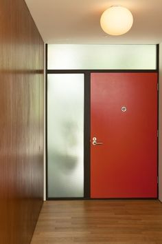 an empty hallway with two red doors and wooden floors